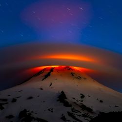 lenticular cloud lit from within by lava from the volcano it surrounds