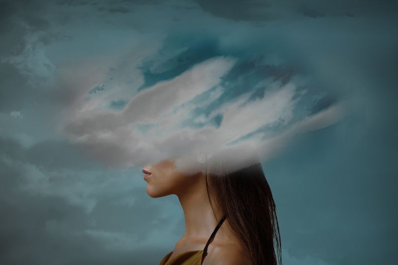 Woman's head covered by clouds.