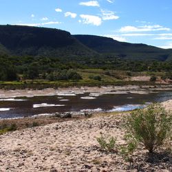 River in Australia showing sandy bank and mountains in the background.