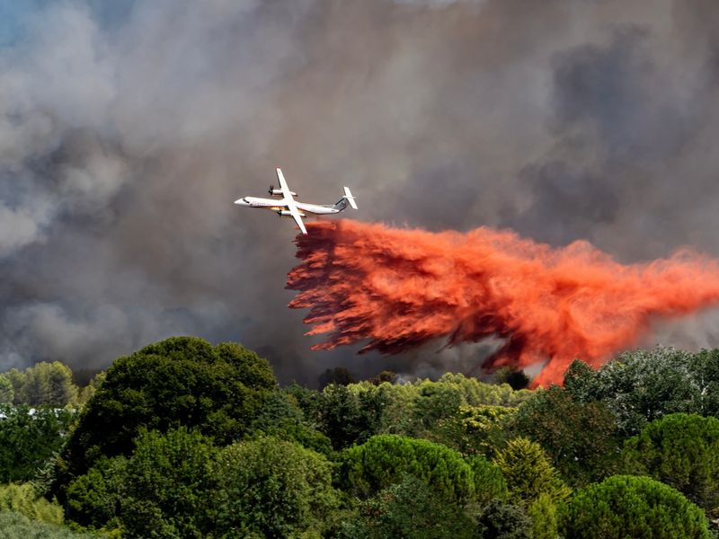 A firefighter plane attempts to put out a wildfire in the scrubland on the road between Aubais and Gallargues-le-Montueux in France.