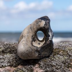 hag stone sitting on a larger rock, the sky visible through the hole