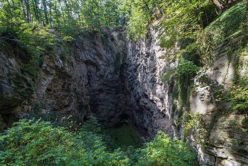 Grass and rocky opening of the Hranice Abyss in Czechia Republic