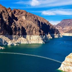 A photo of lake mead surrounded by high cliffs that show a distinct line that separates the old water levels with the brown cliffs 