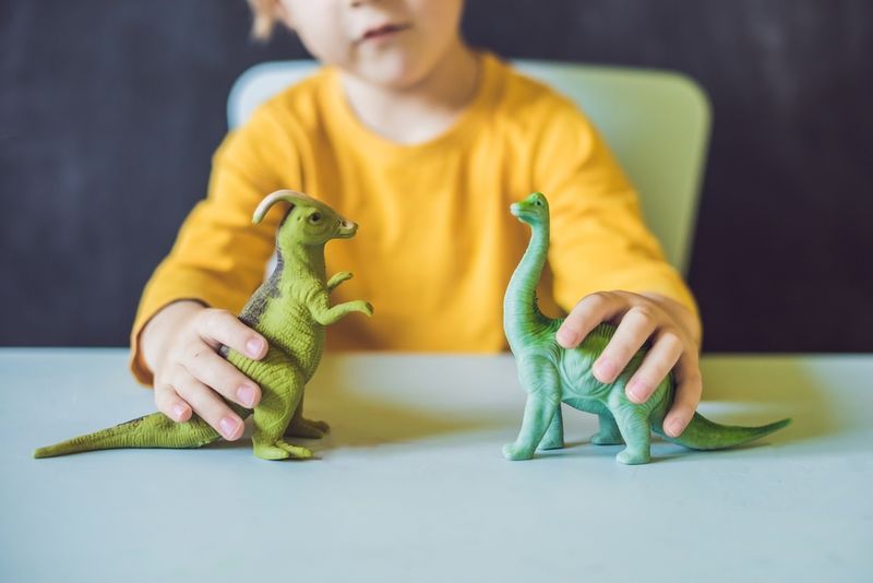 Young boy playing with dinosars doing the voice parts for both 