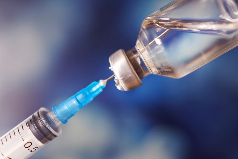 Close up of a syringe entering a vaccine vial.