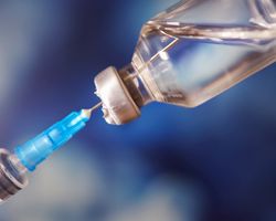 Close up of a syringe entering a vaccine vial.