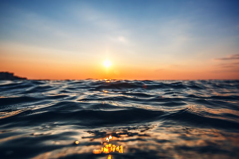 A picture of the sun setting over the sea, from very close to the water