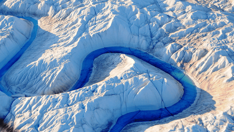 A blue river curves around Greenland's Ice Sheet.