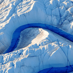 A blue river curves around Greenland's Ice Sheet.