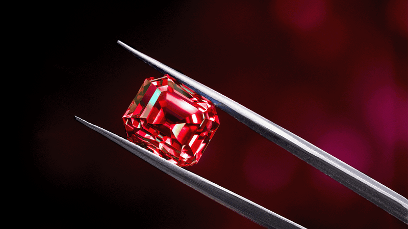 Red diamond held in silver steel tweezers