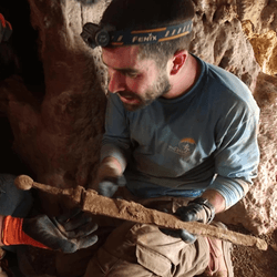 Researcher holding a Roman sword in a cave.